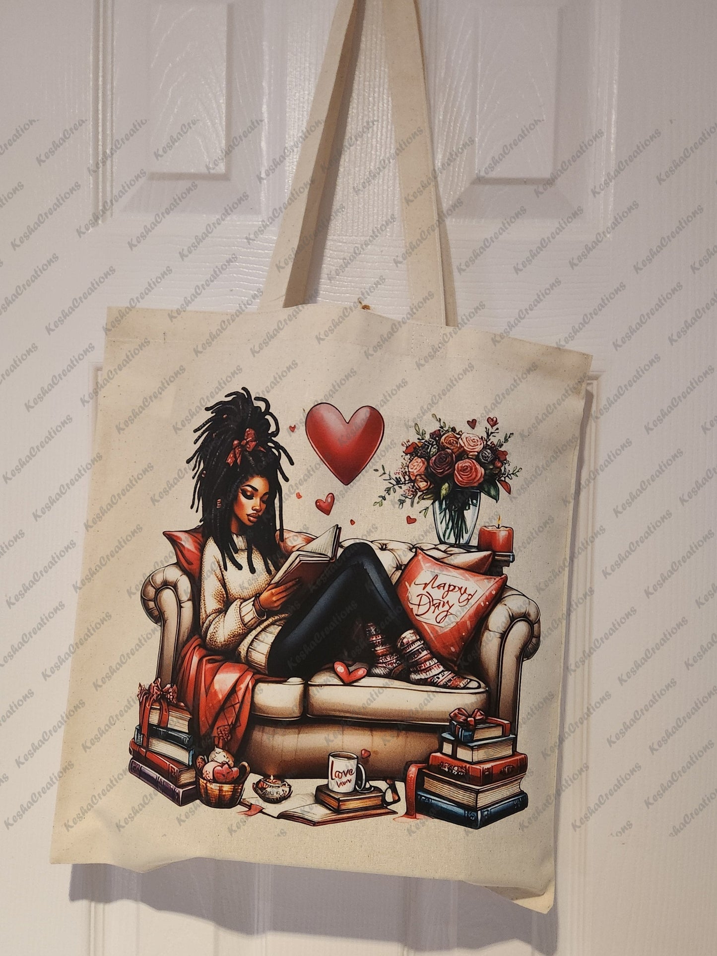 Image of a tote bag featuring a DTF transfer of an African American woman with locs sitting on a cozy couch, reading a book. The design includes elements like a heart, a bouquet of roses, stacks of books, a "Happy Day" pillow, a mug that says "Love," and other cozy decor, all in a warm, inviting setting.