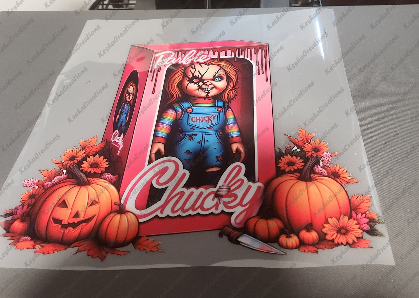DTF transfer design of Chucky inside a pink Barbie-themed box, with pumpkins, flowers, and a knife, labeled 'Chucky' at the bottom.