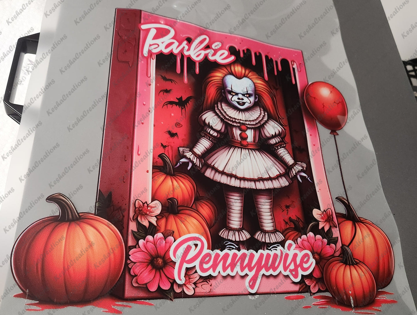 DTF transfer design of Pennywise inside a pink Barbie-themed box, surrounded by pumpkins, flowers, and a red balloon, with 'Pennywise' written at the bottom.