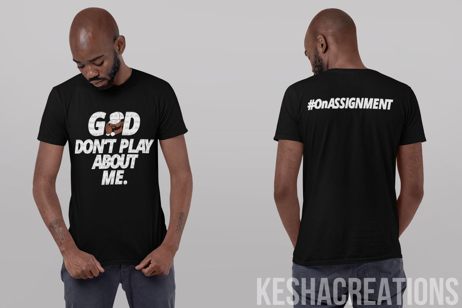 Man wearing the 'God Don’t Play About Me' T-shirt from KeshaCreations Exclusive God Line, showcasing the front and back views. The front design features bold typography with a vibrant character illustration and Psalm 91 text overlay, while the back displays the phrase '#OnAssignment.' The model stands against a neutral background, looking down.