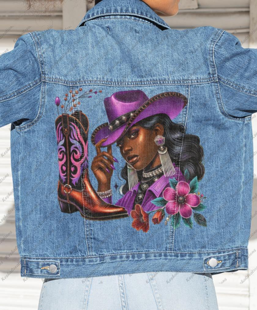 Woman flexing her arms in a denim jacket printed with a colorful DTF transfer of a cowgirl in a purple hat and matching boots, surrounded by bold flowers. A stylish and empowering KeshaCreations design.